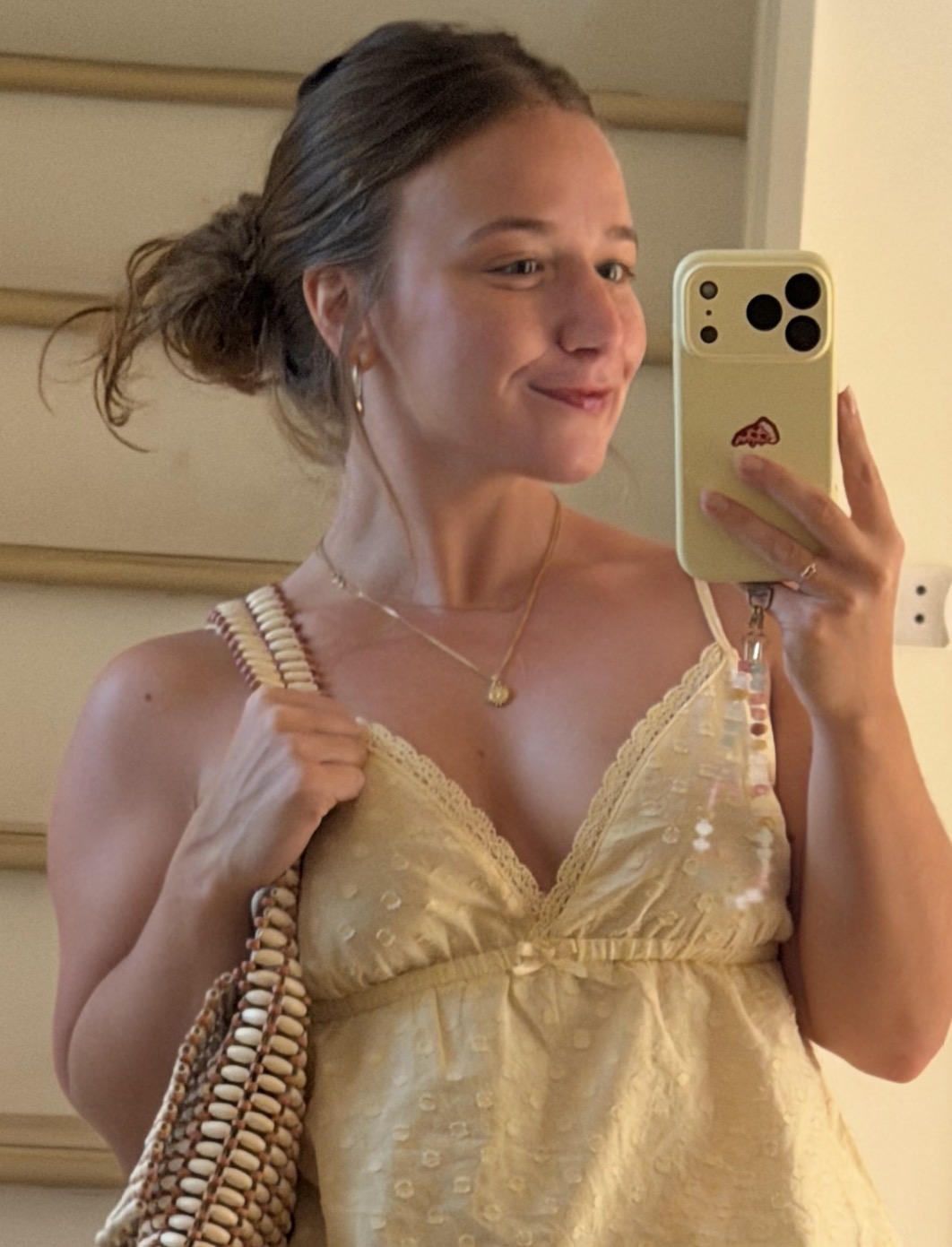 Alaina taking a mirror selfie in a yellow dress