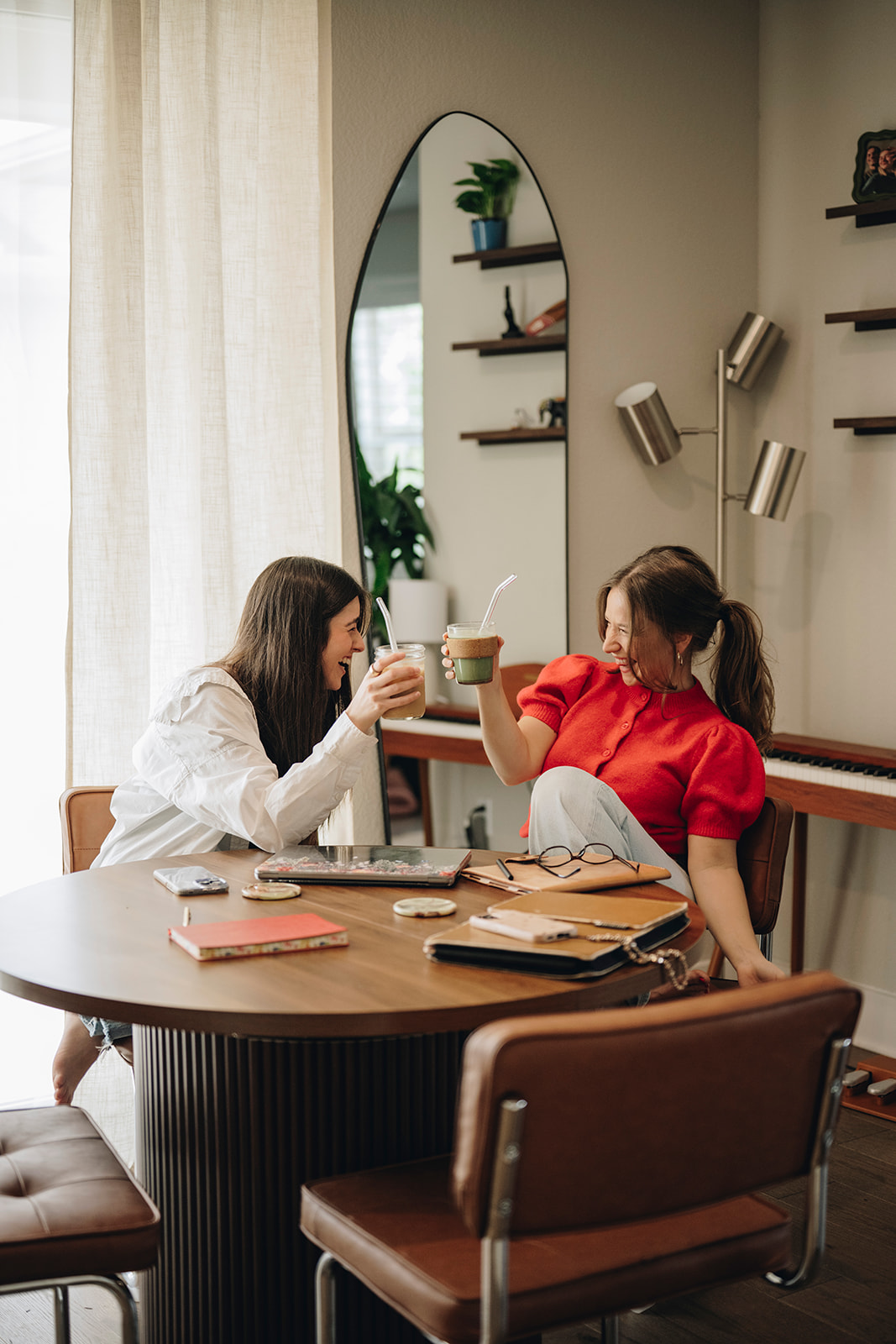 Two women working and sharing green drinks around a table